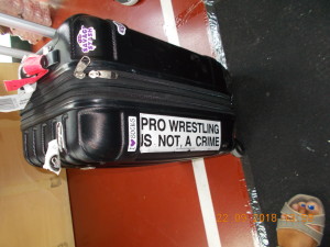 Nella foto, in alto: la scritta adesiva sulla valigia di Holidead. "Il wrestling professionale non è un crimine" 